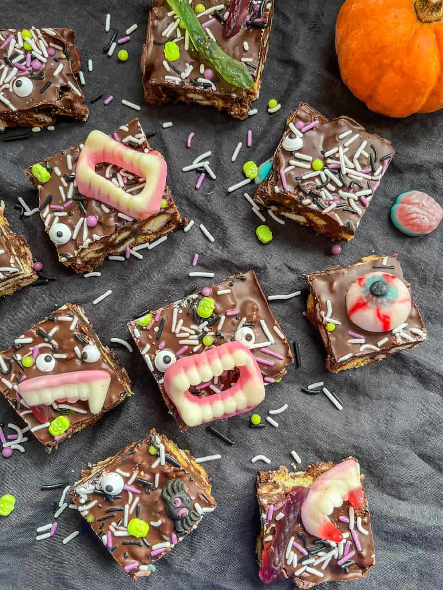 Squares of rocky road decorated with Halloween sprinkles, candy eyes and candy teeth, eyeballs and snakes.