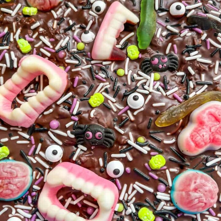 A slab of Halloween rocky road topped with Halloween sprinkles, candy eyes and candy teeth, brains, skulls and snakes.