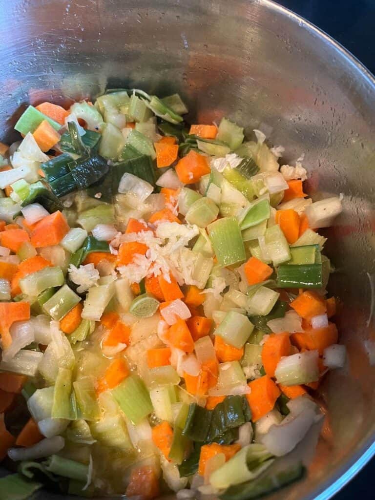 A silver pan of chopped carrots, onions, leeks and garlic.