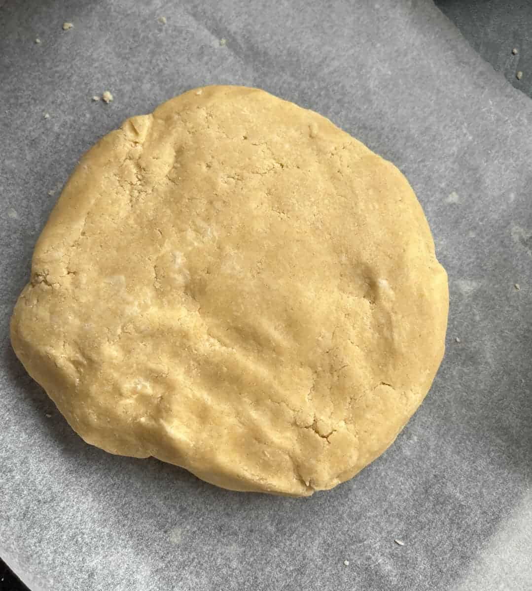 A ball of unbaked pie crust dough on a piece of baking parchment.