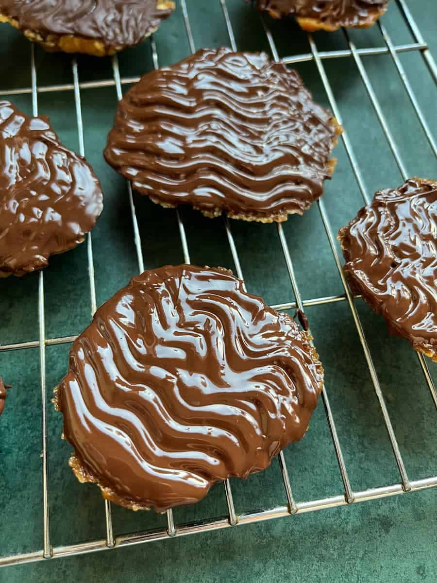 Florentines dipped in melted chocolate on a wire cooling rack.