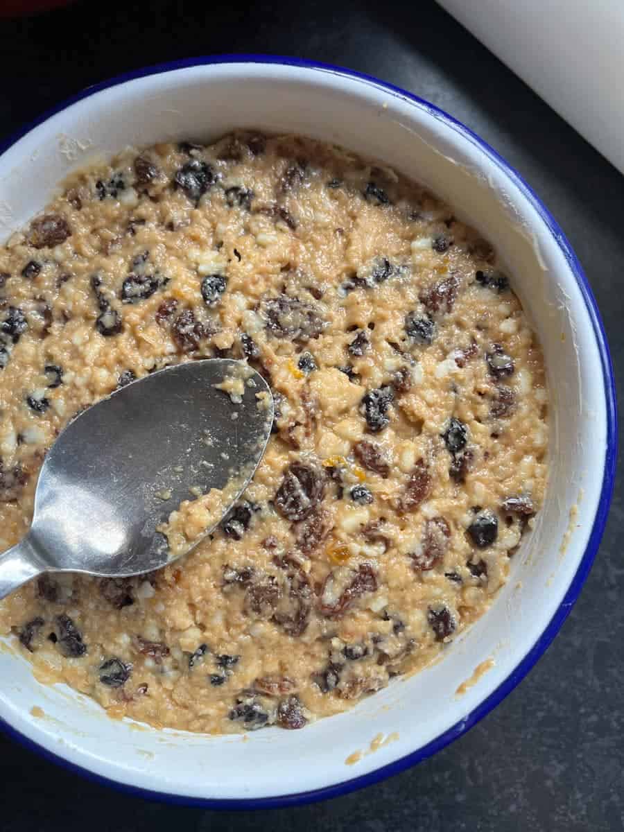 Raw Christmas pudding mixture spooned into a blue and white enamel pudding dish.