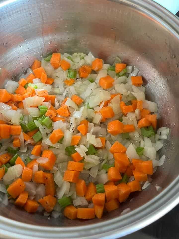 diced onions, celery and carrots in a silver saucepan.