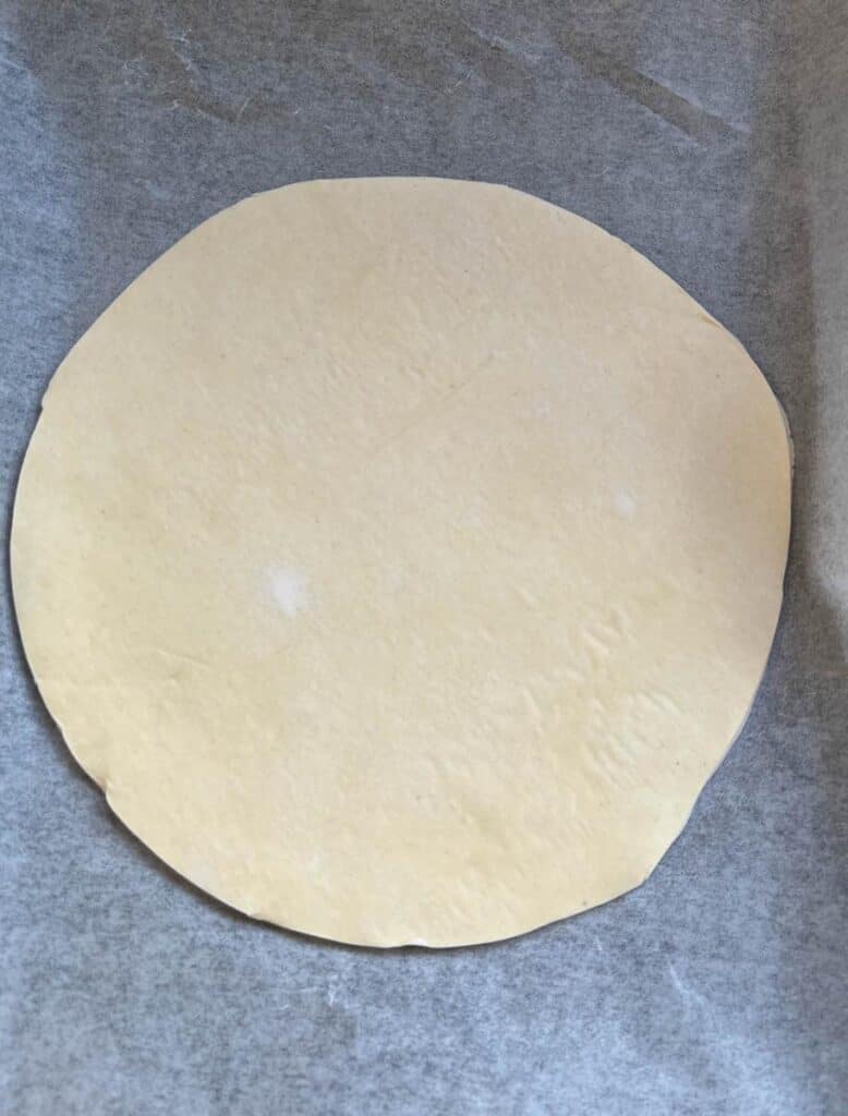 A circle of puff pastry on a lined baking tray.