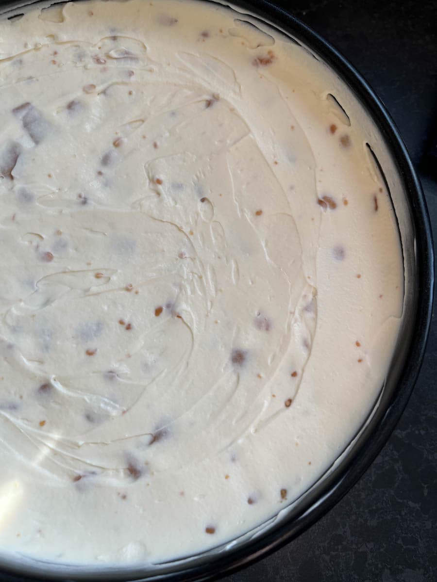 A no bake cheesecake in a round black springform cake tin.
