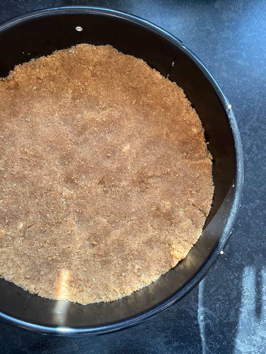 A black springform round cake tin with a biscuit base.