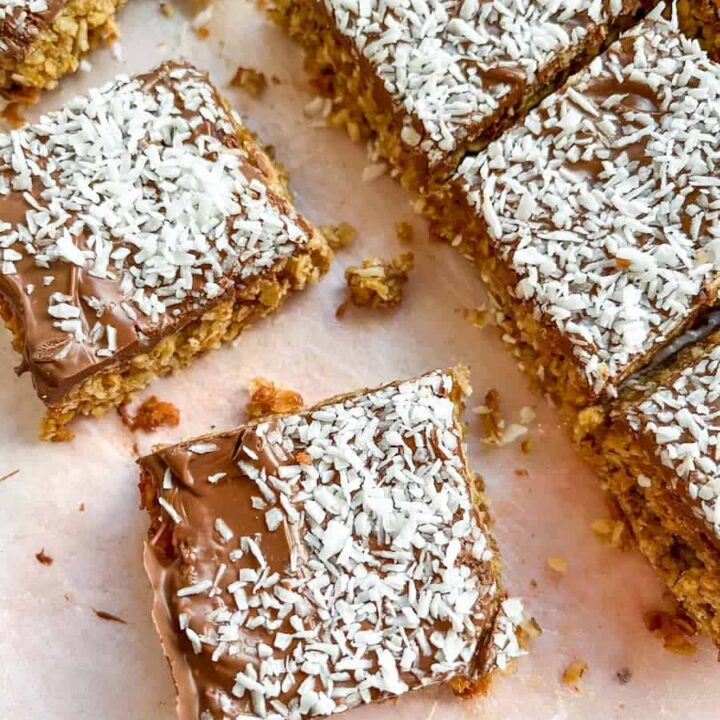 Flapjack bars covered in melted milk chocolate and sprinkled with dessicated coconut.