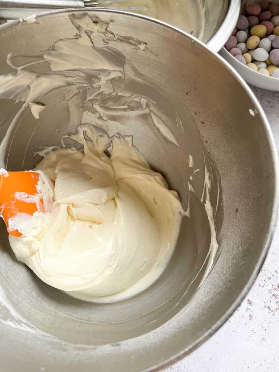 Asilver bowl of whipped cream cheese with an orange spatula.