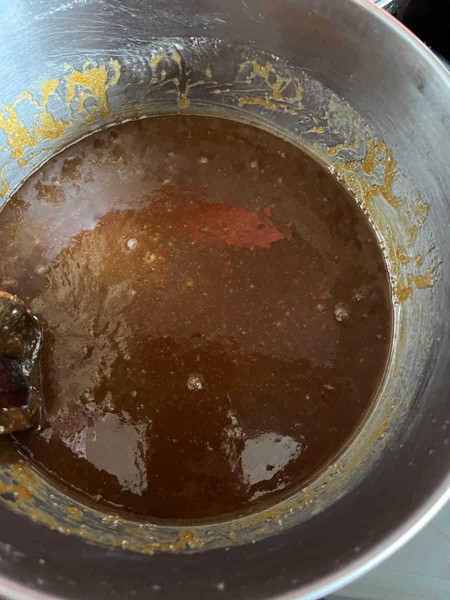 A silver pan of melted butter, brown sugar and biscoff spread.