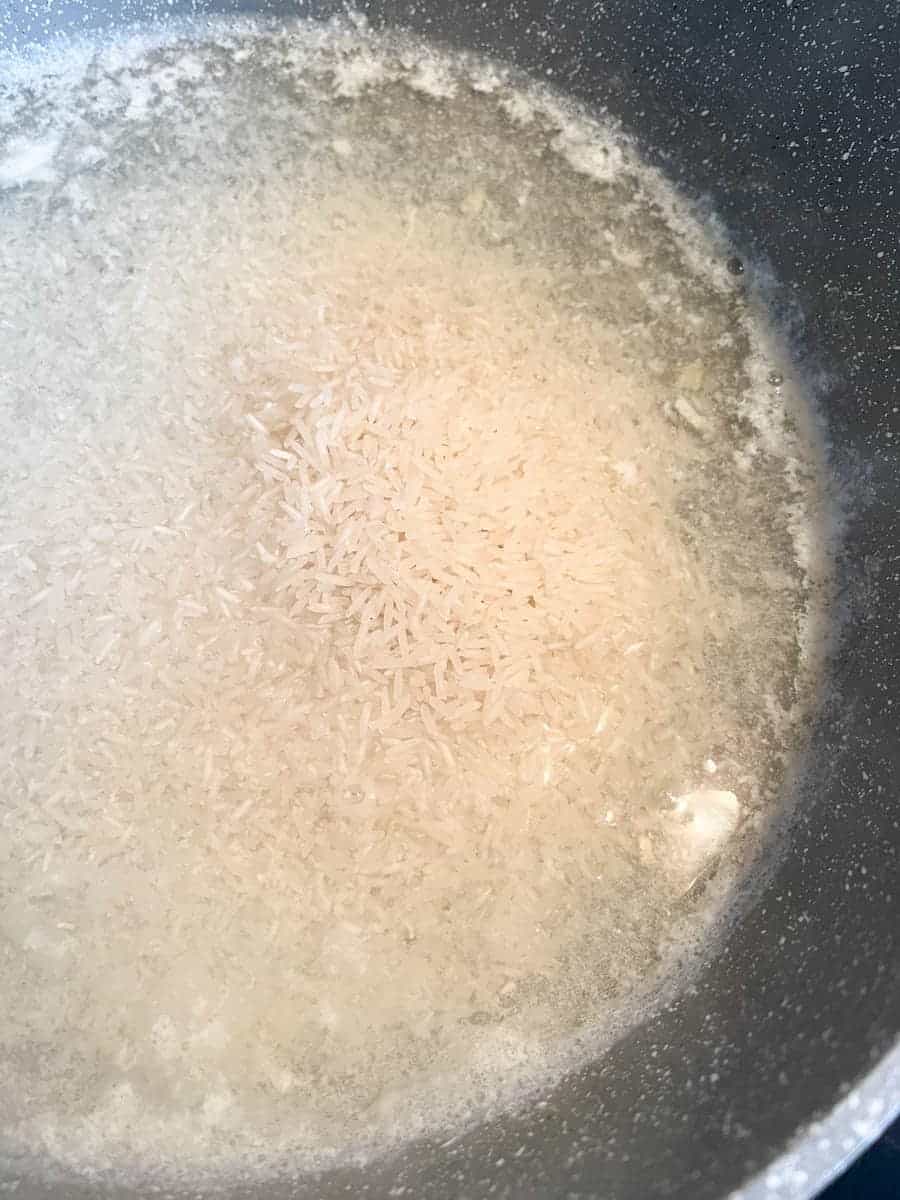 A pan of white rice cooking in boiling water.