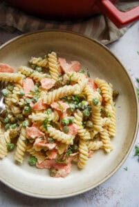 A bowl of Fusilli pasta with peas, dill and capers in a creamy sauce.