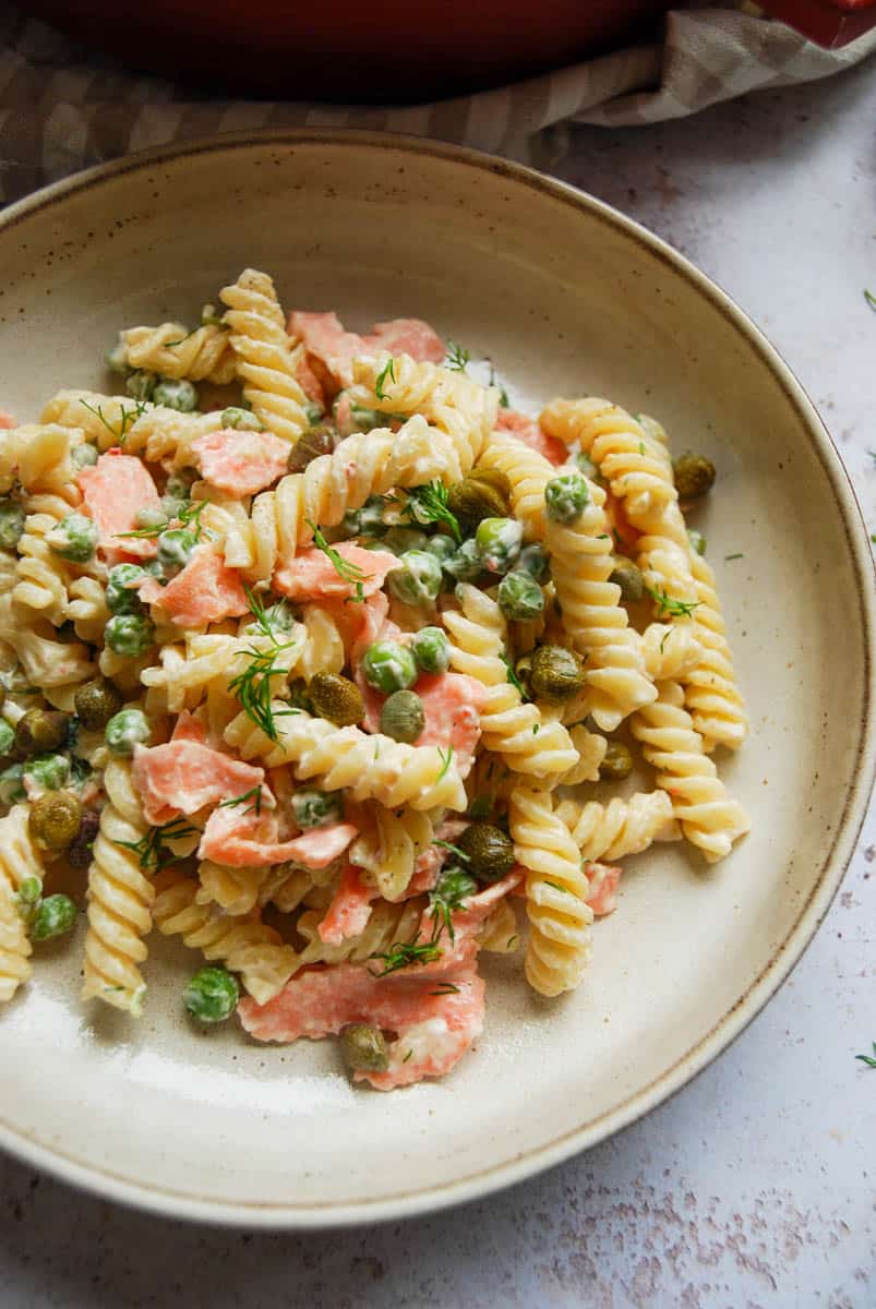 A bowl of Fusilli pasta with smoked salmon, peas, fresh dill and capers in a creamy sauce.