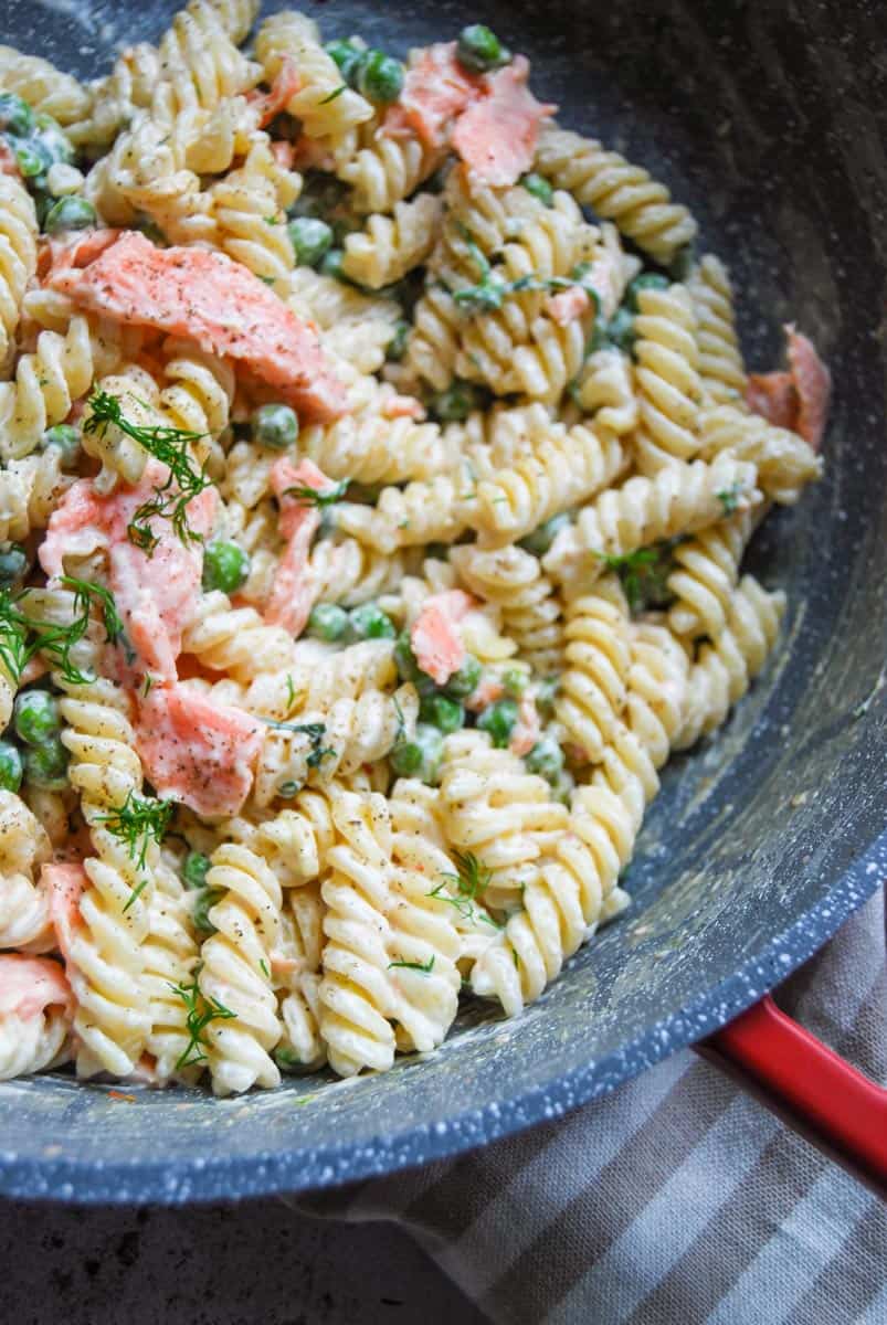 A pan of Fusilli pasta with smoked salmon, peas and dill in a creamy sauce.