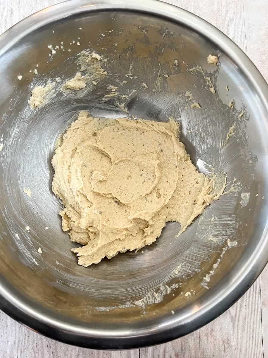 A silver mixing bowl with butter and sugar beaten together.
