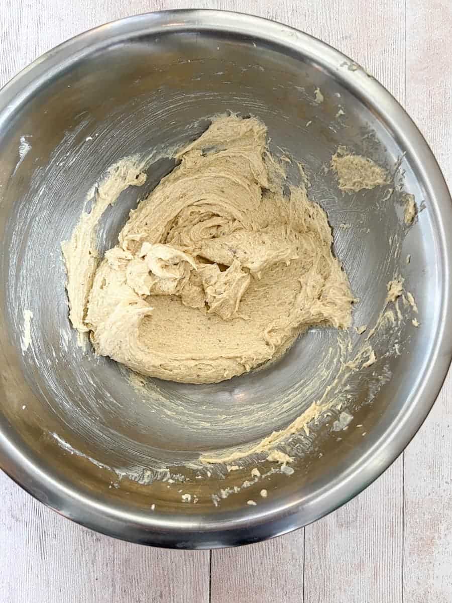 A large silver mixing bowl of creamed butter and brown sugar.