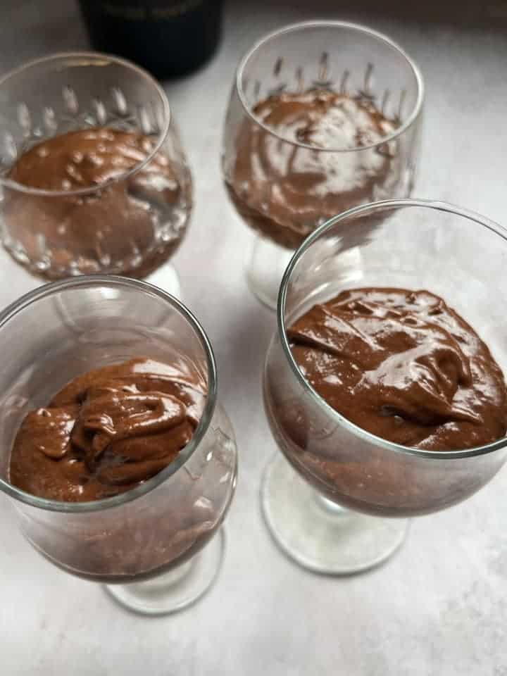 four wine glasses filled with chocolate mousse.