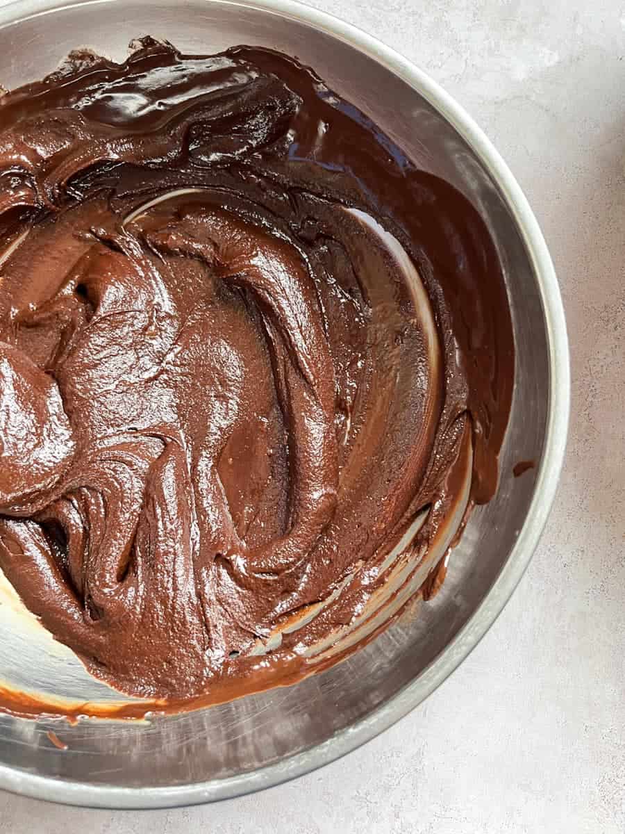 A silver bowl of melted chocolate and egg yolks beaten together.