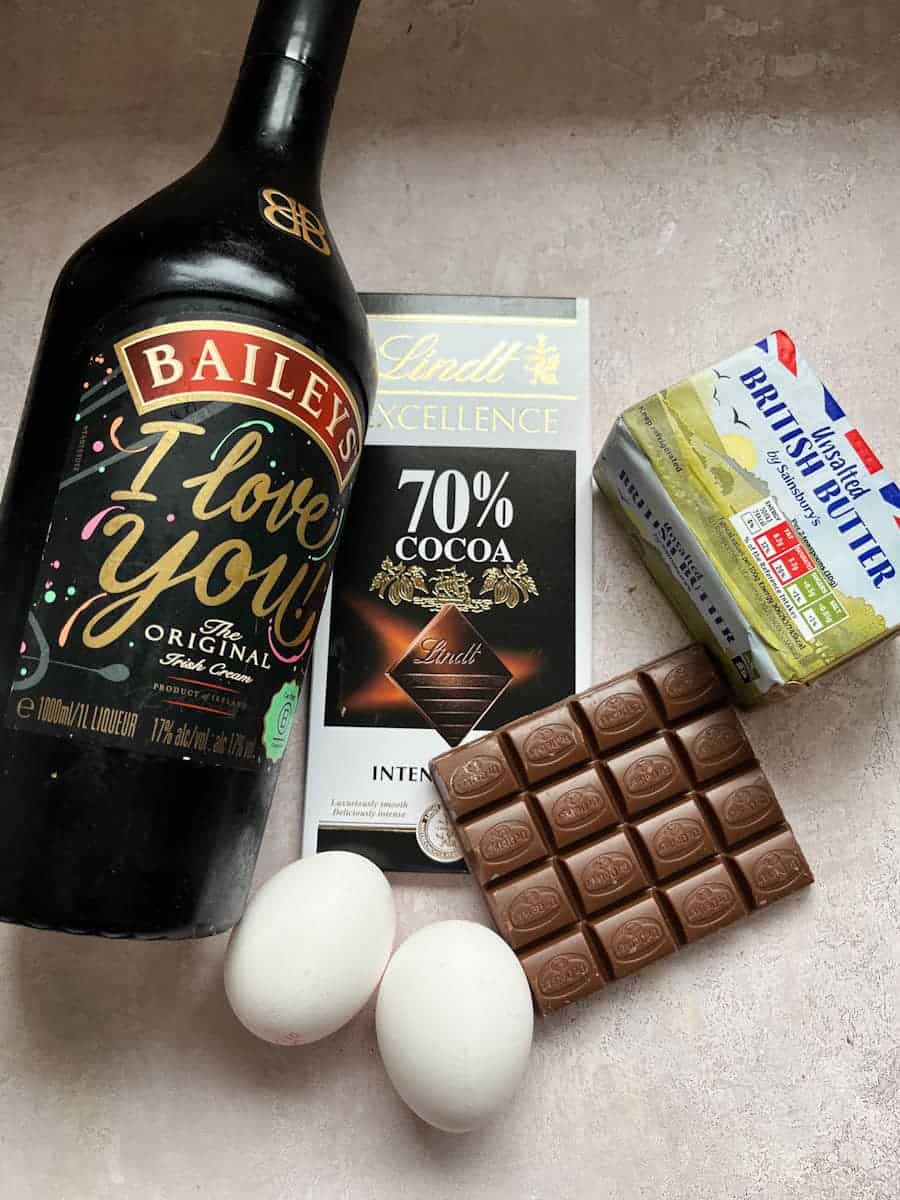A bottle of Baileys Irish cream liqueur, bars of plain and milk chocolate, a packet of butter and two eggs.