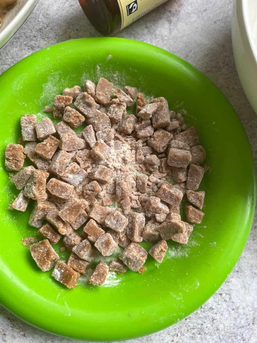 A green plate of chopped fudge pieces dusted with flour.