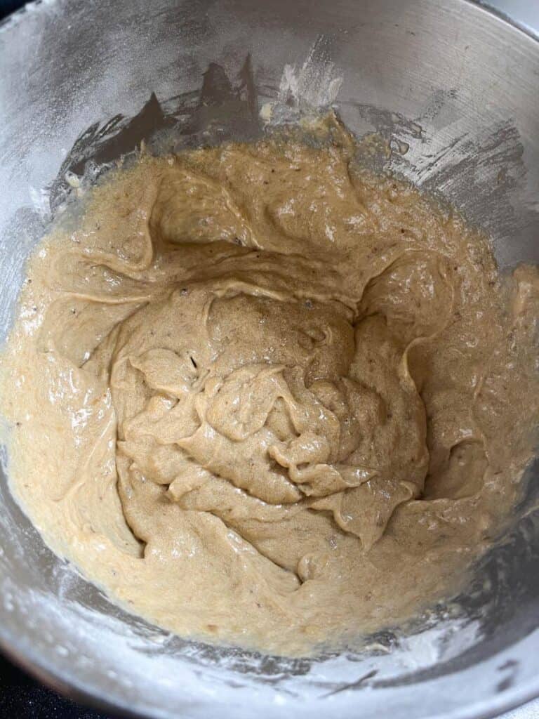 Banana loaf batter in a silver mixing bowl.