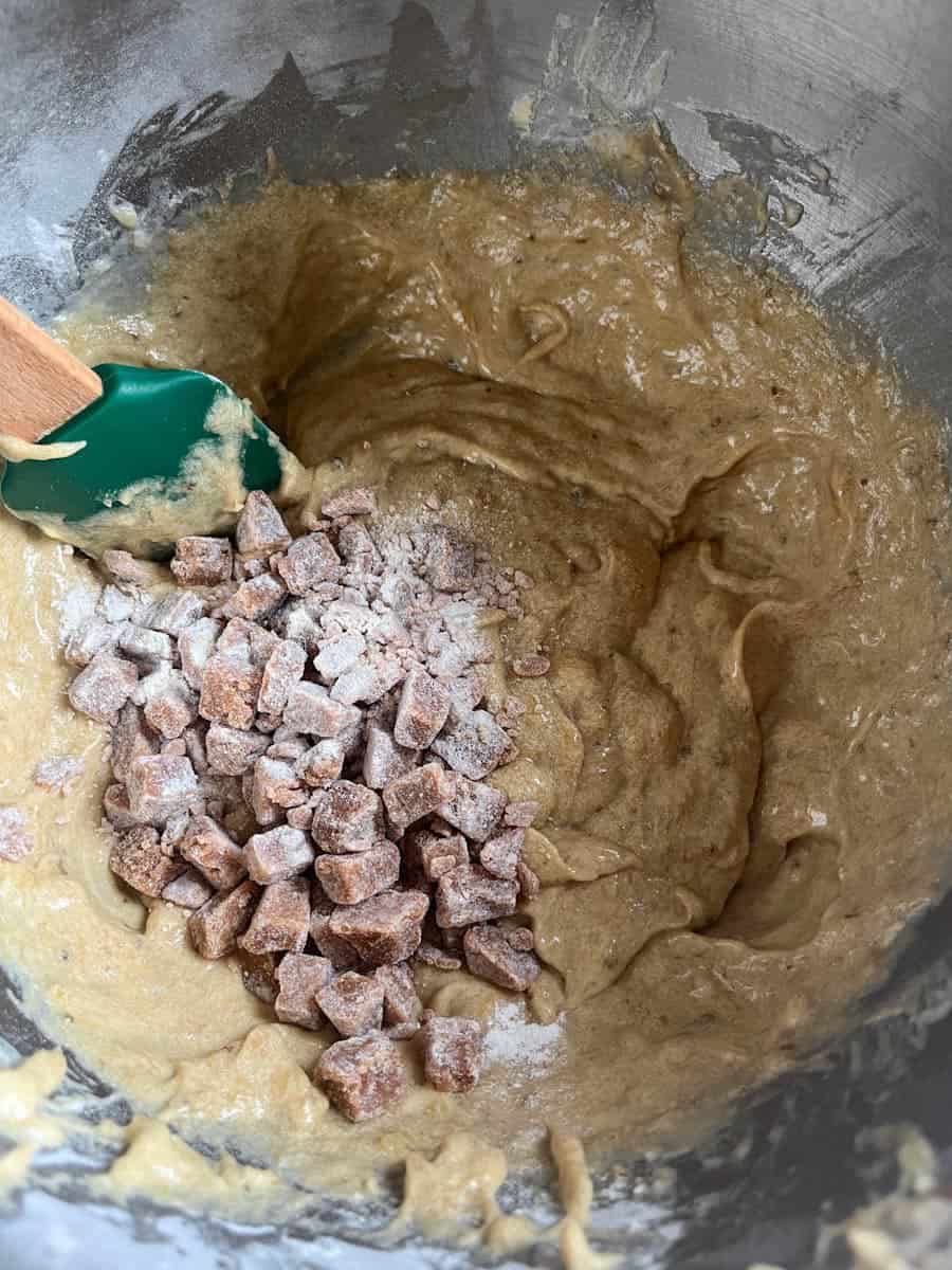 chopped fudge pieces being folded into a bowl of banana bread batter.