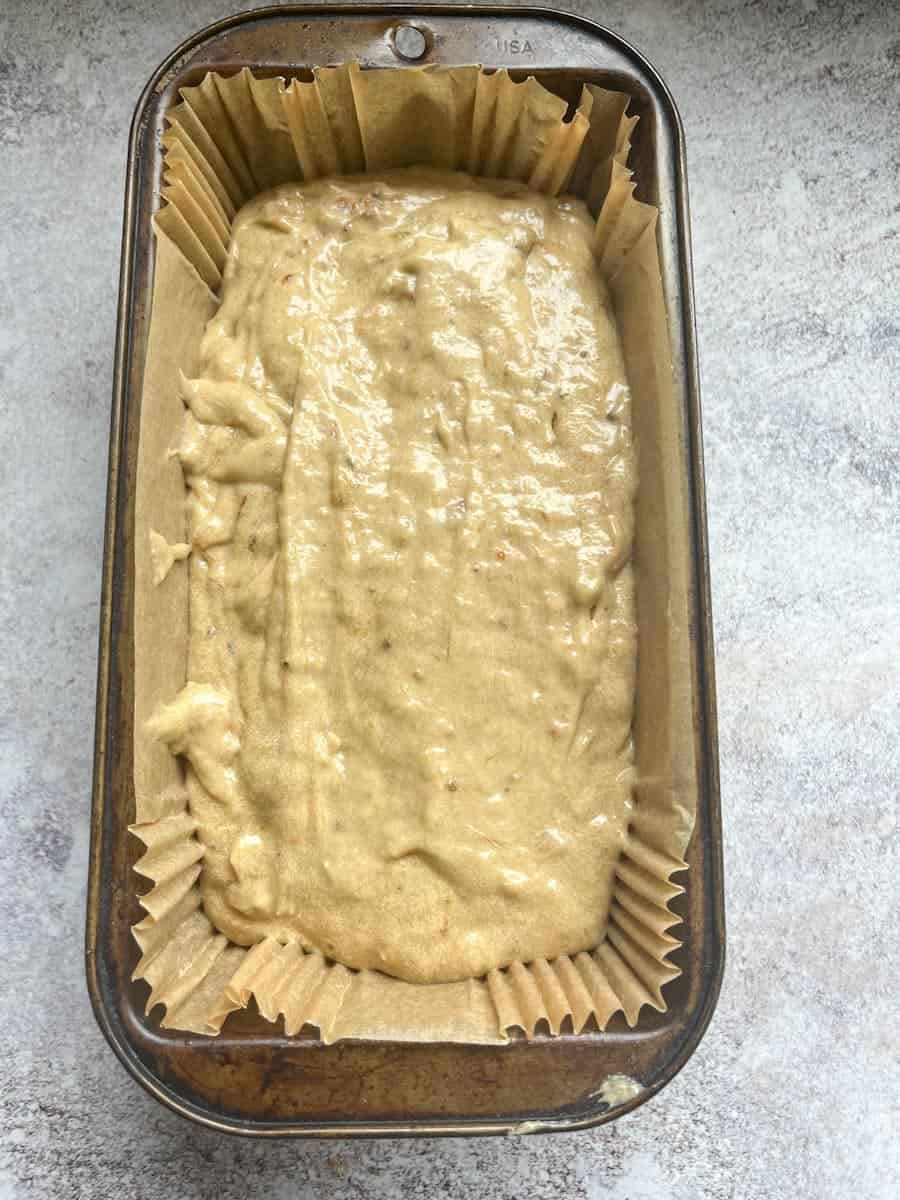 Banana bread batter inside a loaf tin lined with a loaf tin liner.