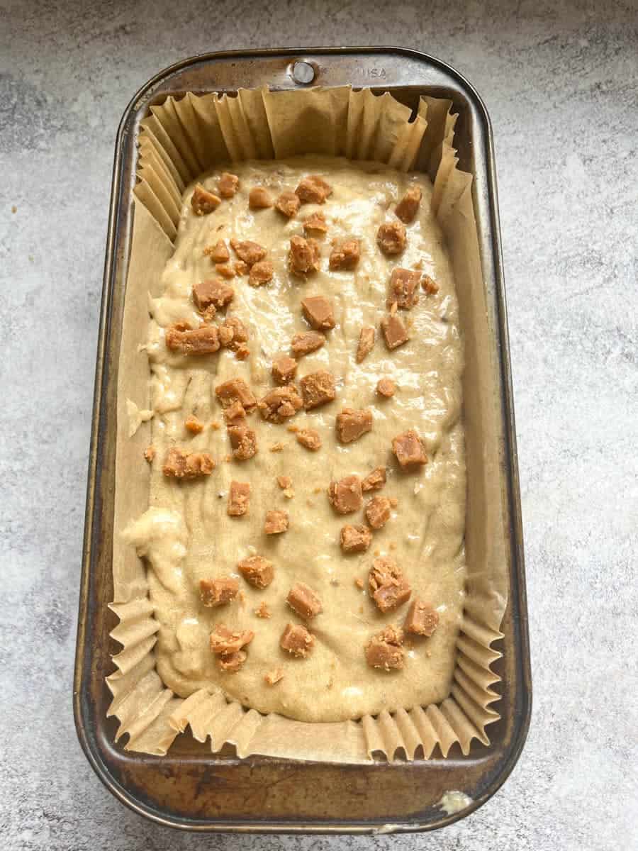An unbaked banana loaf topped with chopped fudge pieces.