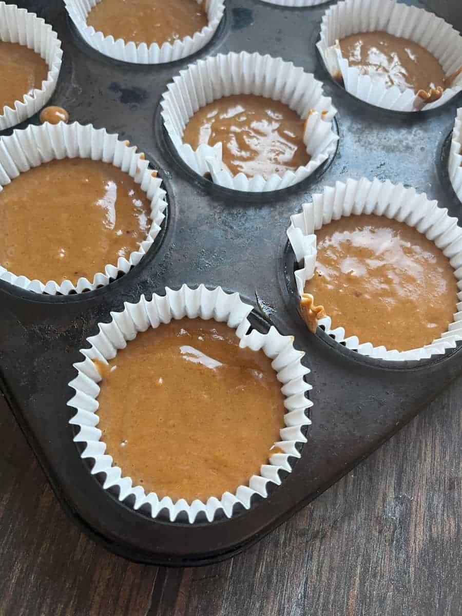A cupcake tin filled with unbaked pumpkin cupcakes.