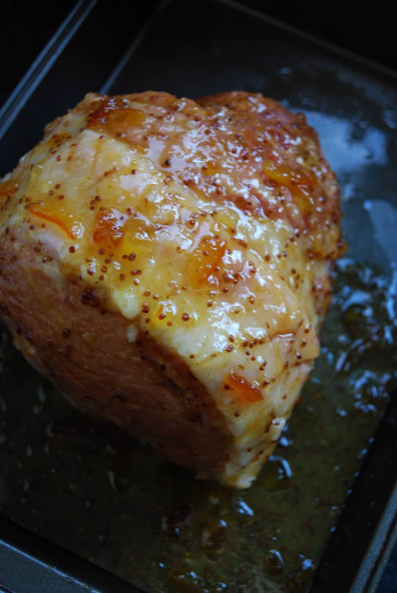 A cooked gammon joint covered in marmalade glaze on a baking tray.
