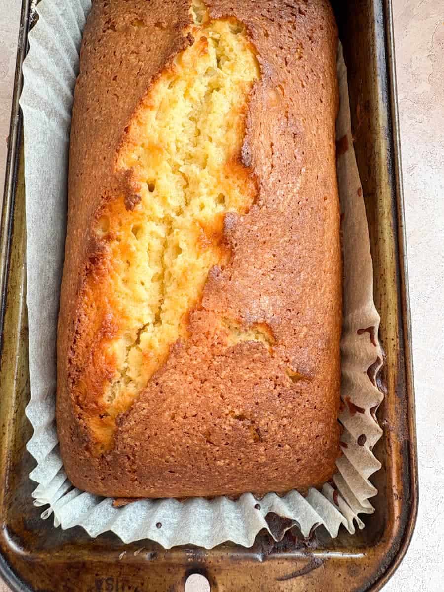 A freshly baked orange loaf cake in a loaf tin.
