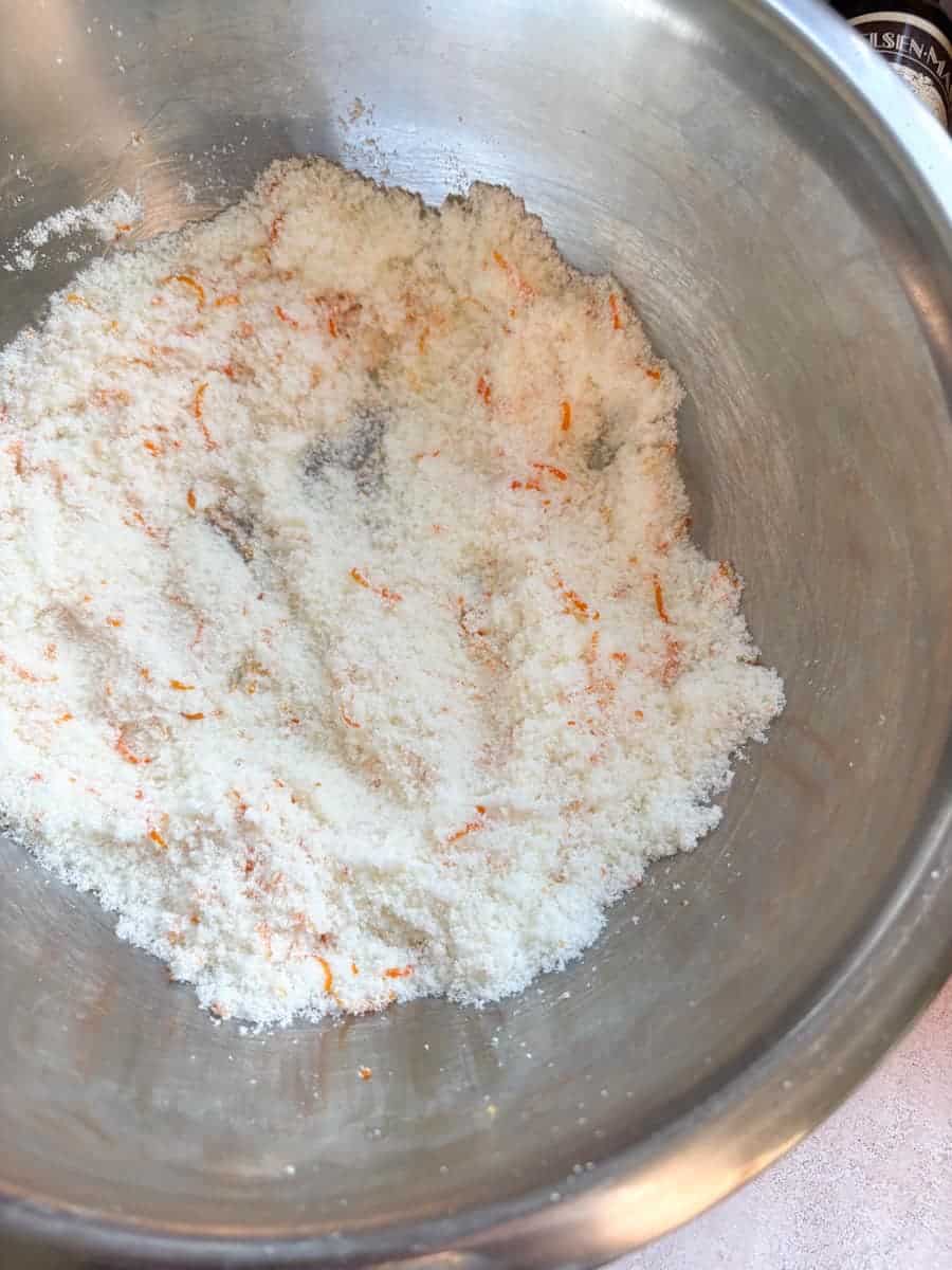 A silver bowl of caster sugar and grated orange zest.