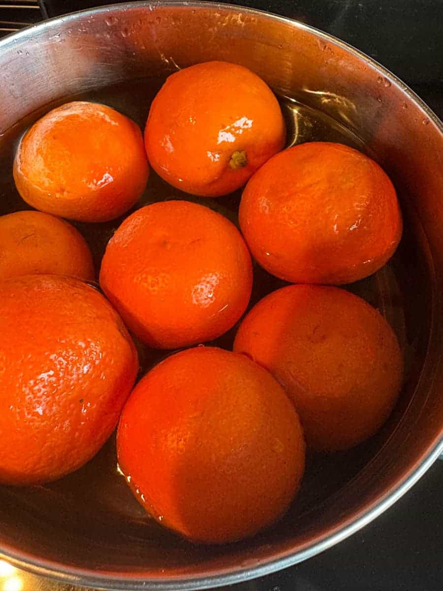 A large silver pan filled with water and eight Seville oranges.