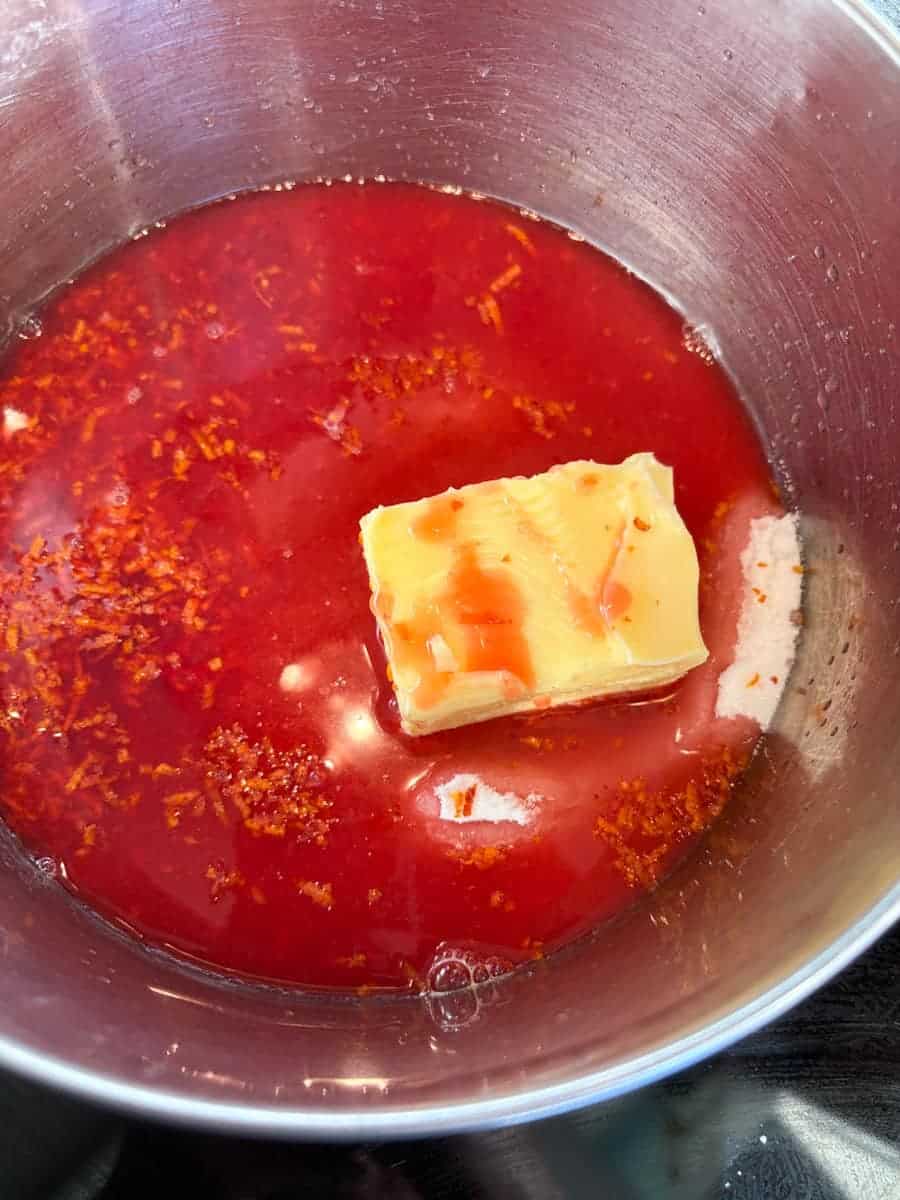 Blood orange juice, orange zest and butter in a silver bowl.