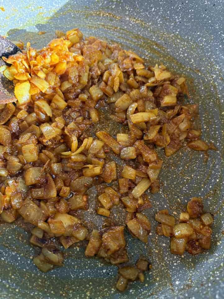 A grey saucepan of cooked onions and spices.