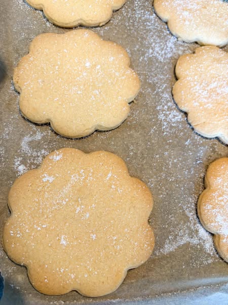 Six pieces of shortbread sprinkled with sugar on a lined baking tray.
