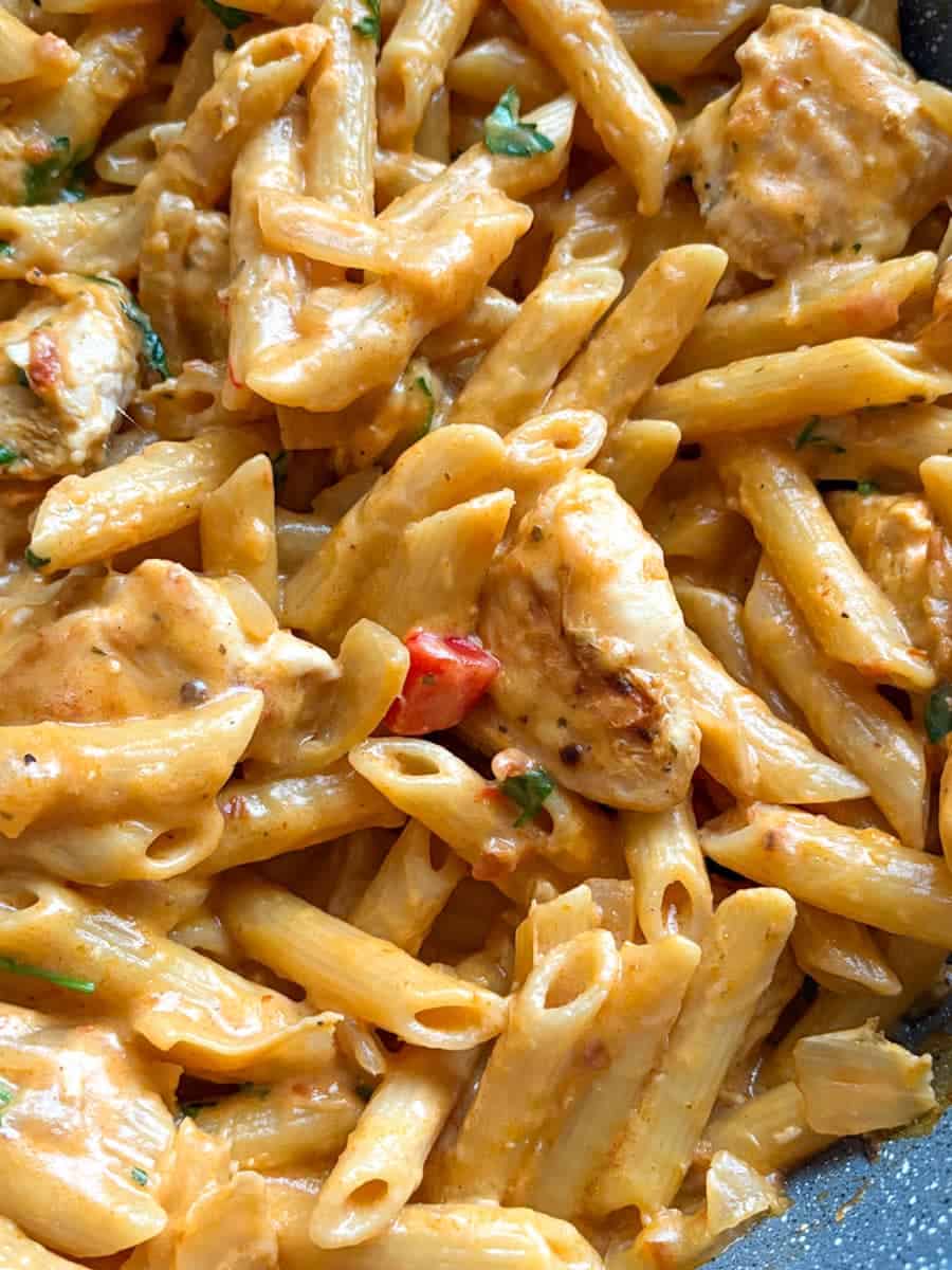 A pan of penne pasta with Peri Peri chicken, diced peppers and onion in a creamy, spicy sauce.
