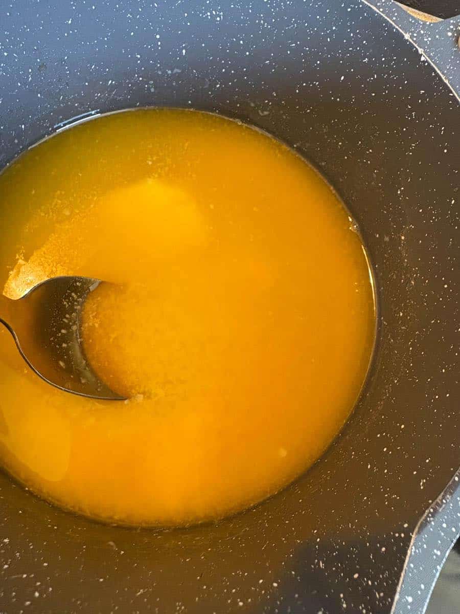A saucepan of melted butter with a gold spoon.