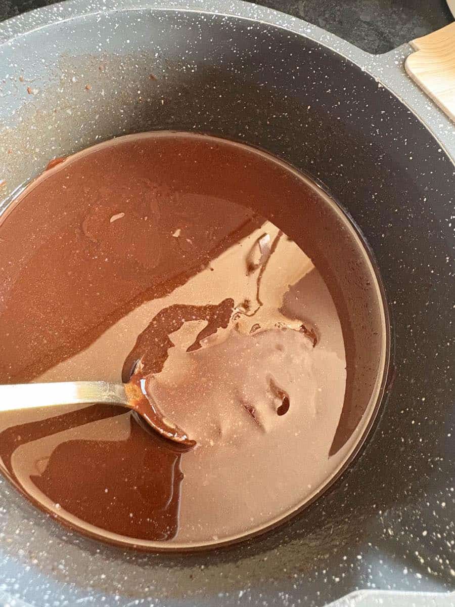 A grey pan of melted butter and chocolate with a silver spoon.