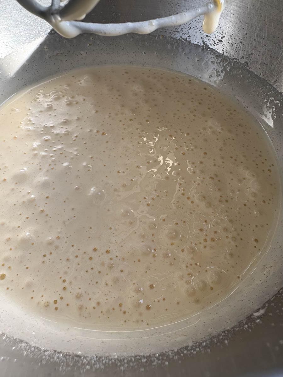 Eggs and sugar whisked together in a silver mixing bowl.