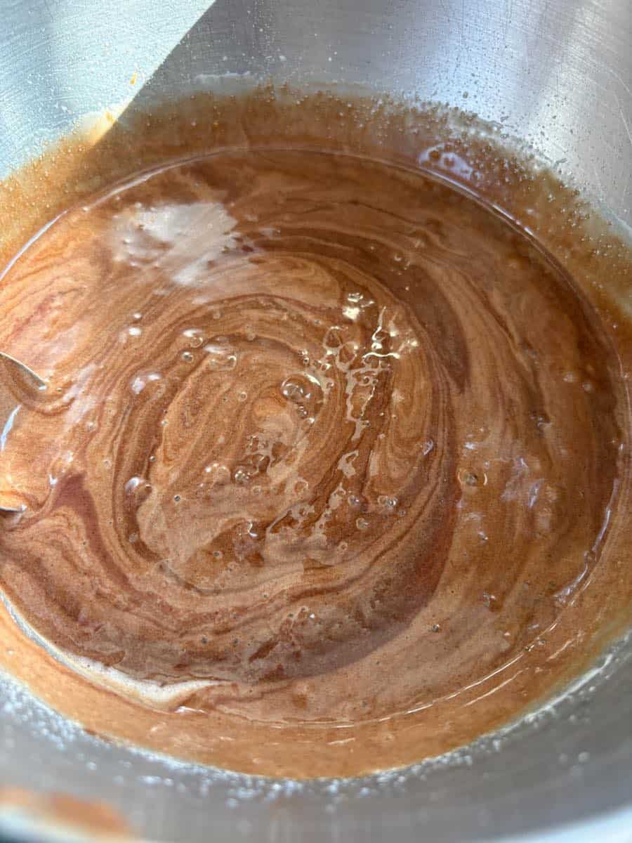 Melted chocolate being stirred into beaten eggs and sugar.