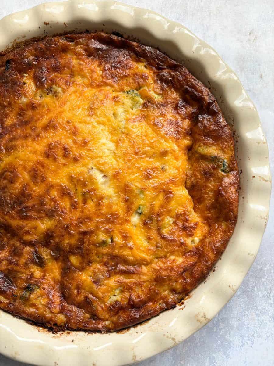 A freshly made crustless quiche in a white pie dish.