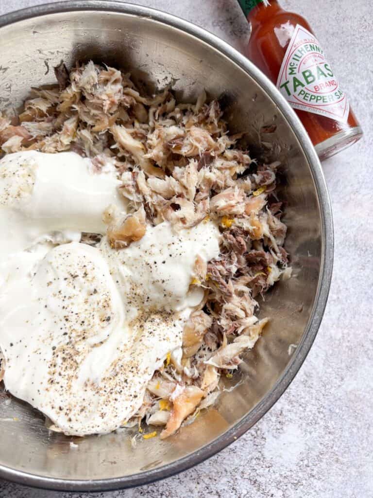 A silver bowl of flaked mackerel fillets, Greek yoghurt and a bottle of Tabasco sauce.