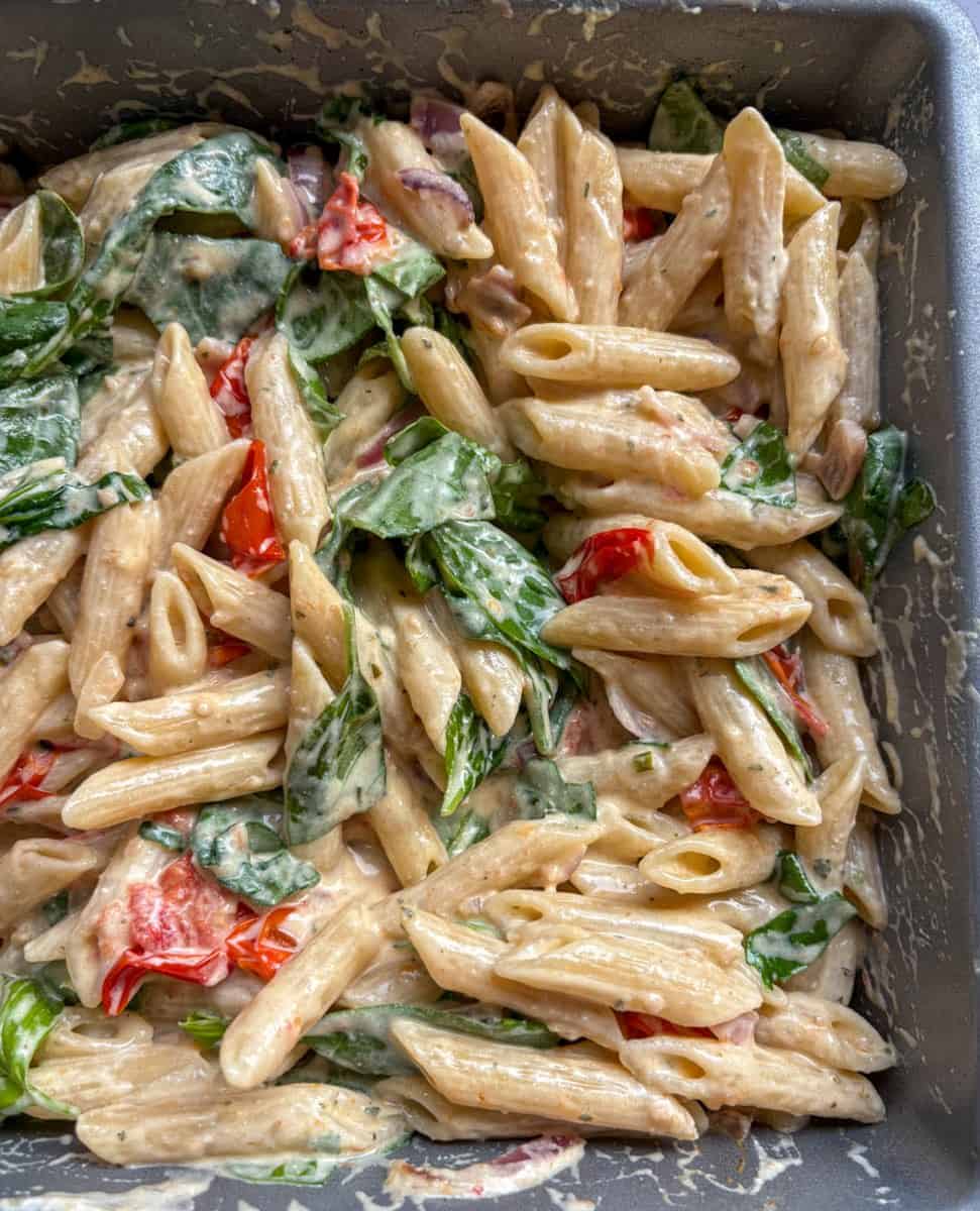 A silver pan of Boursin pasta - Penne pasta in a creamy Boursin cheese sauce, tomatoes and chopped spinach.