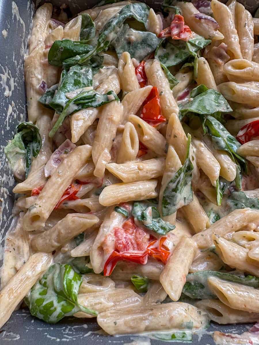 A silver pan of Boursin pasta - Penne pasta in a creamy Boursin cheese sauce, tomatoes and spinach.