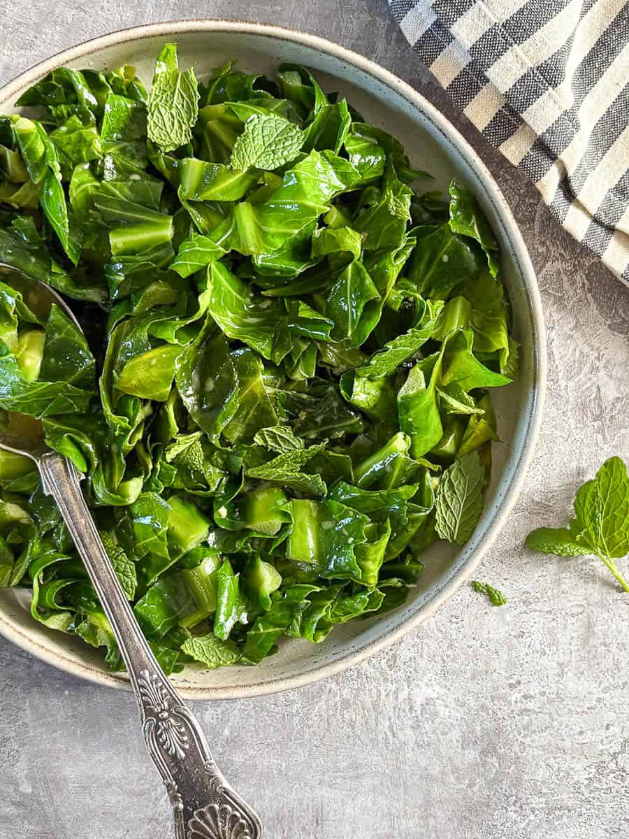 A bowl of sliced Spring greens with a silver serving spoon.