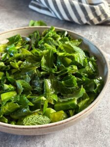 A bowl of sliced Spring greens with fresh mint leaves.
