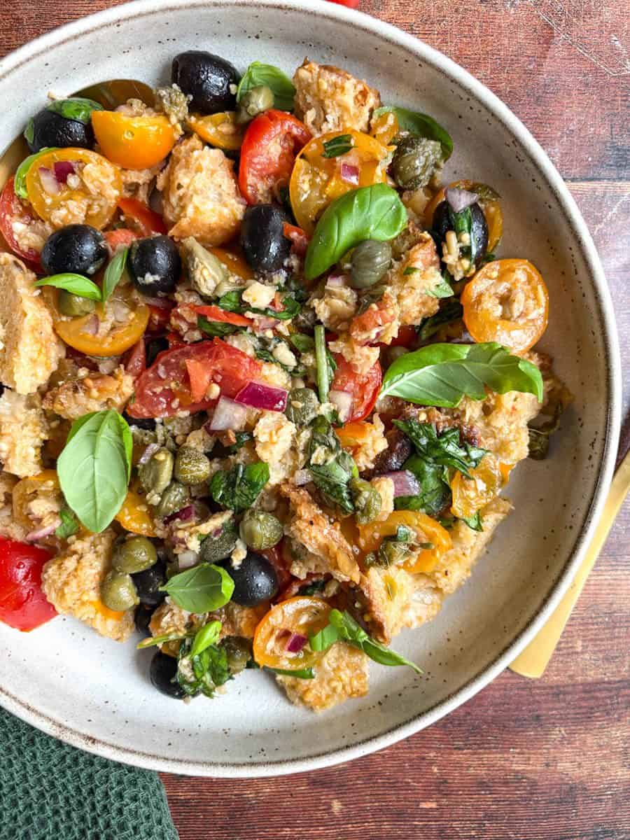 A rustic Italian Panzanella salad with crusty bread, sliced red onion, tomatoes, olives, capers and fresh basil tossed in a red wine vinaigrette.
