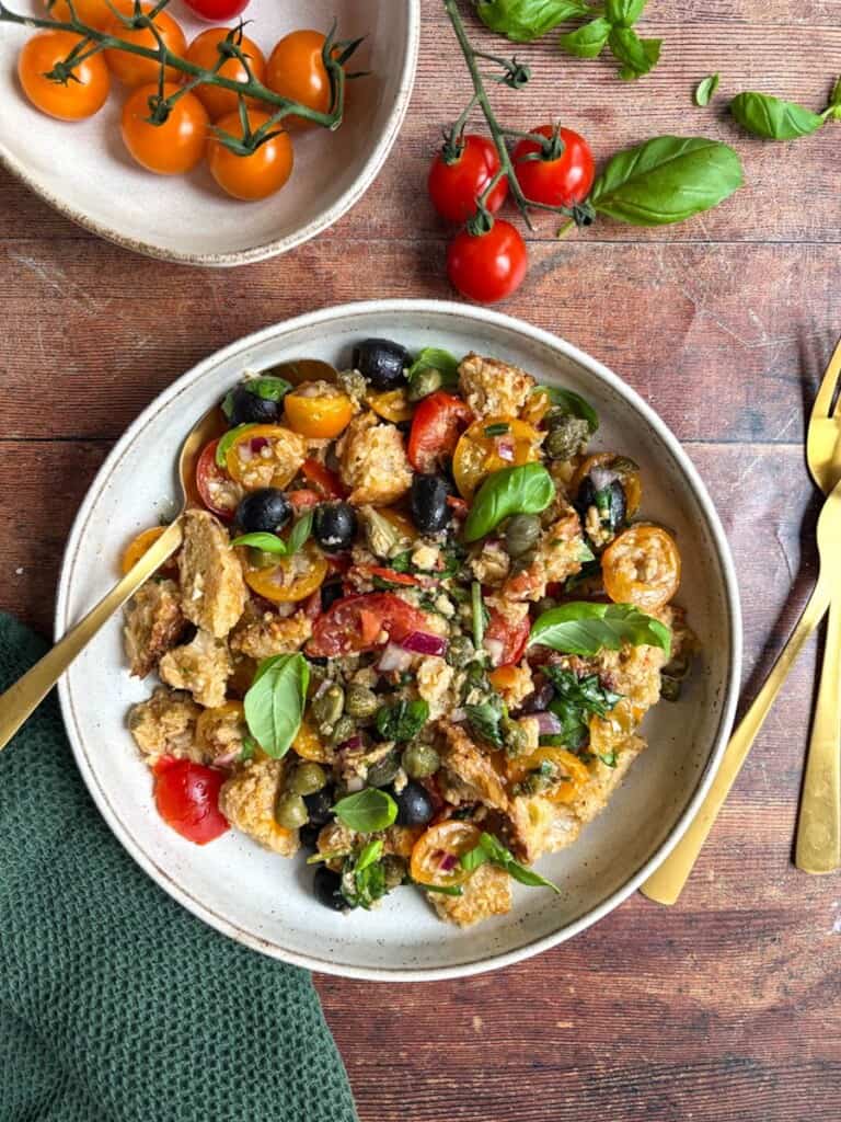 A rustic Italian Panzanella salad with crusty bread, sliced red onion, tomatoes, olives, capers and fresh basil tossed in a red wine vinaigrette.